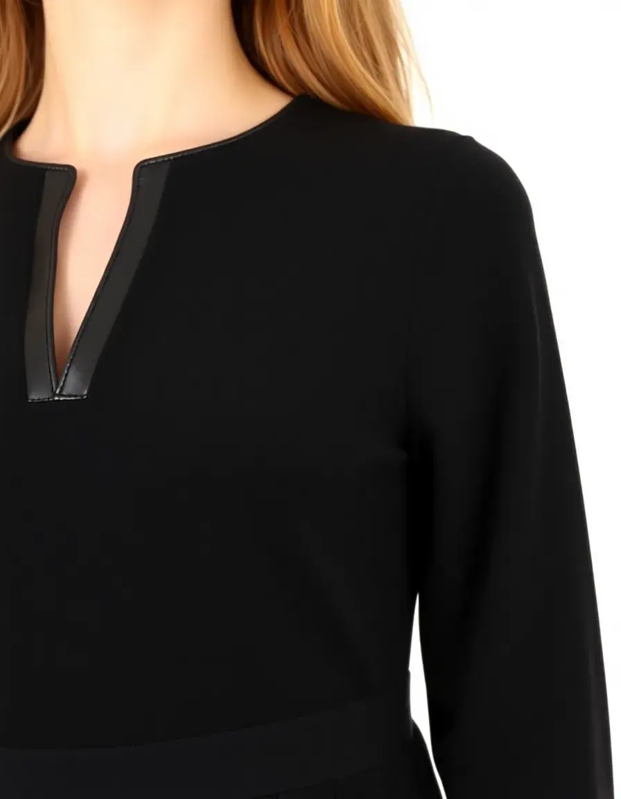 Model wearing a black dress with intricate leather trim details